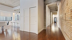 Un interior moderno con zona de cocina, paredes blancas y una pared de ladrillo.