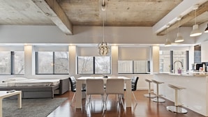 Una cocina moderna con comedor, ventanas amplias y una lámpara colgante original.