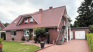 A two-story brick house with a red-tiled roof, a front porch, and a garage. - Tammens "Naturblick" - comfortable and beautiful (Papenburg)