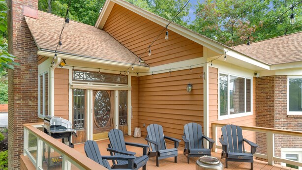 A covered deck with Adirondack chairs, a grill, and a trash can. - 5 BR Wintergreen House w/ Game Room, 75” TV, Ping Pong, Foosball, Wet Bar & Deck (Nellysford)