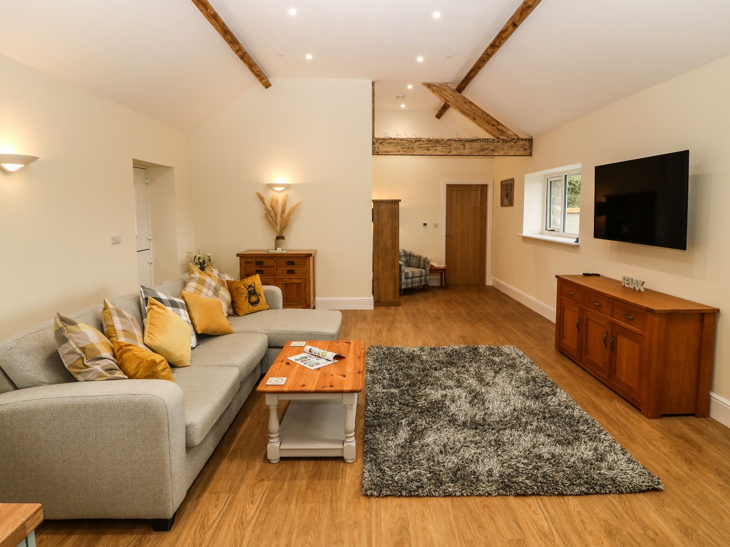A living room with a grey sofa, wooden coffee table, and a grey shag rug.