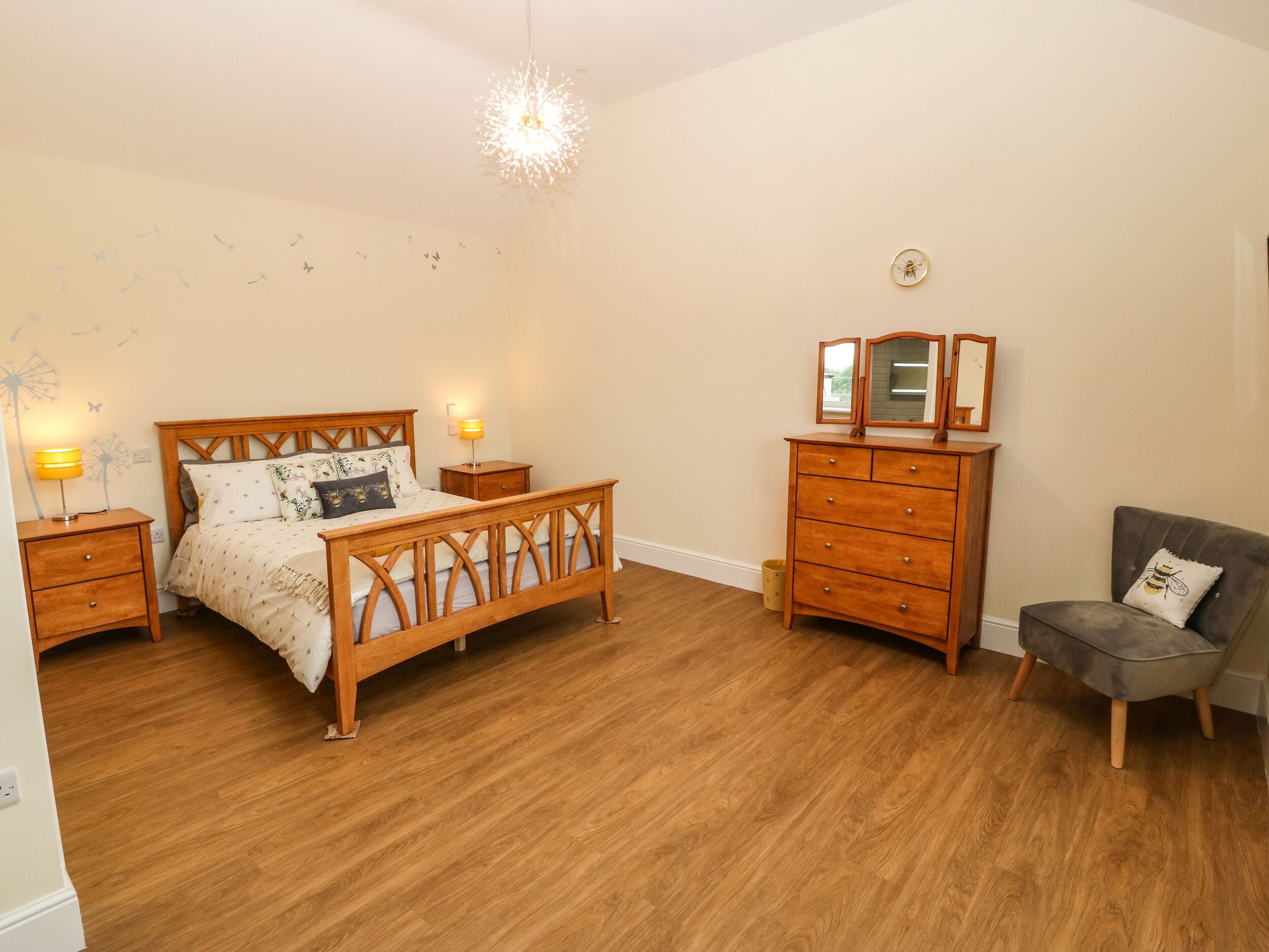 A bedroom with a wooden bed, nightstands, a dresser, and a chair.