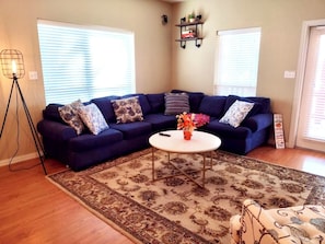 A living room with a dark blue sectional sofa, a patterned rug, and a small white coffee table. - Riverfront home with hot tub, playground, kayaks, and amazing panoramic views! (Trinity)