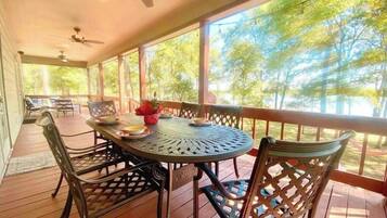 Un área de comedor al aire libre techada con una mesa redonda, sillas y ventiladores de techo.