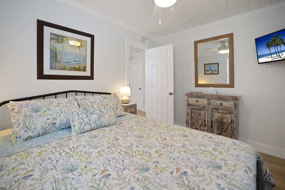 Un dormitorio con cama, cómoda, puerta y decoración en la pared.