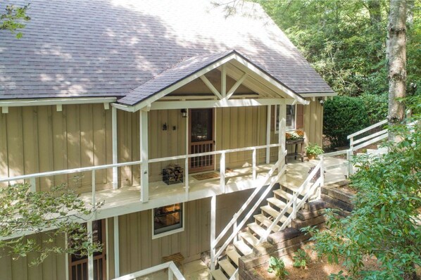 A two-story wooden house with a balcony and a staircase leading to the upper floor.