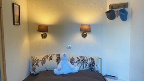 Ein Schlafzimmer mit einem großen Bett, zwei Wandleuchten, einer kleinen Ablage mit Dekoration und einem Stofftier auf dem Bett.