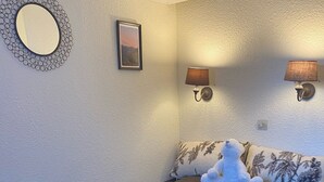 Ein Schlafzimmer mit einem großen Bett, einem runden Spiegel, einem gerahmten Bild und zwei Wandleuchten.