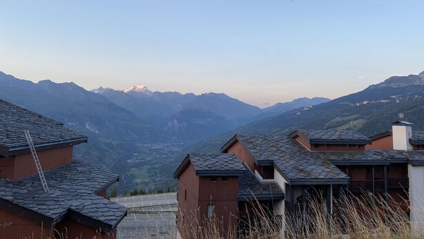 Ein Wohngebiet mit Häusern mit schrägen Dächern und einer Bergkulisse im Hintergrund.