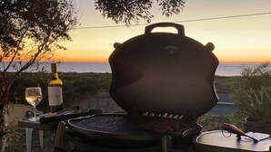 Un barbecue avec un steak dessus, une bouteille de vin et un verre de vin posés sur une table.