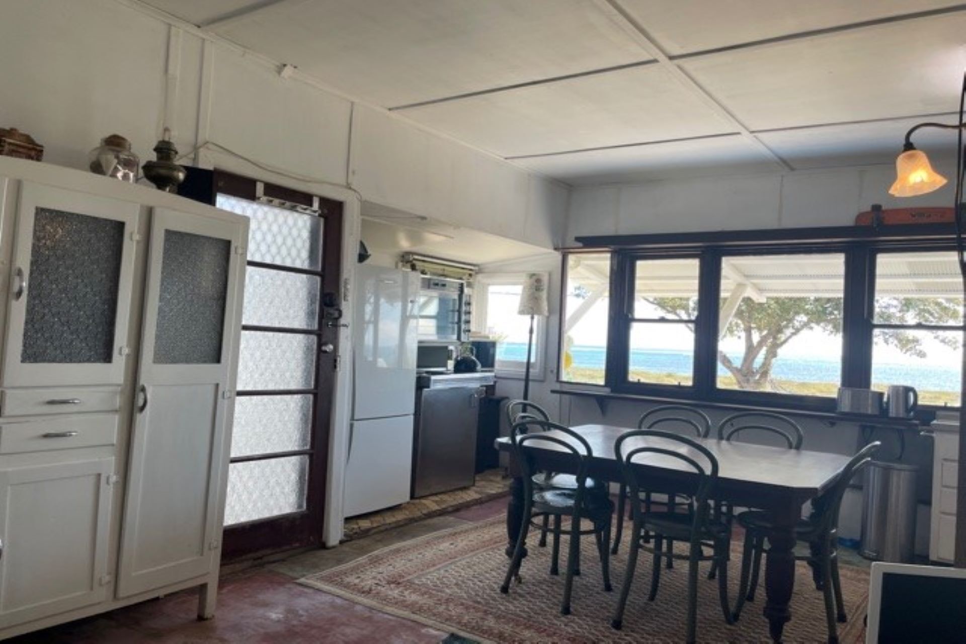 A kitchen with a dining area, a view of the sea, and a window with a view of the beach.