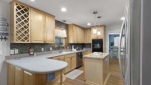 Une cuisine moderne avec des meubles en bois, un plan de travail en granit et des appareils électroménagers en acier inoxydable.