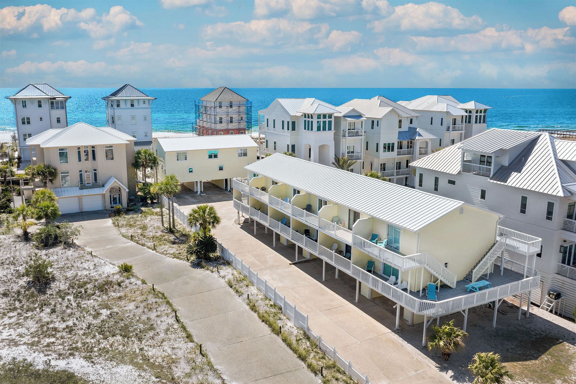 A coastal hotel with multiple-story buildings, a beachfront promenade, and a clear view of the ocean.