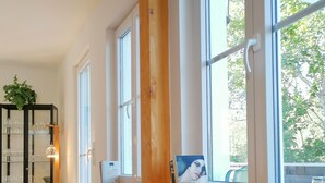 Una habitación acogedora con una silla de mimbre, una mesa con una vela y una estantería con cristalería.