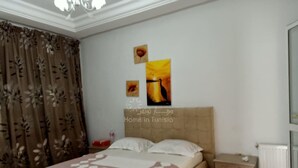 Une chambre à coucher avec un lit, des tables de chevet, un radiateur et des rideaux.