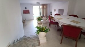 Un coin repas avec un escalier menant à une autre pièce, une table à manger entourée de chaises et des plantes en pot.