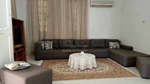 Un salon avec un canapé, un pouf et une table basse ronde.