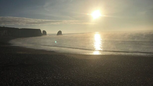 A beach with the sun setting over the horizon, creating a calm and serene atmosphere. - The Bay Cabin, secluded retreat Freshwater Bay (Freshwater)