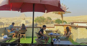 A terrace with outdoor seating, a view of pyramids, and a stone wall. - Standard Deluxe Single Room (Gizah)