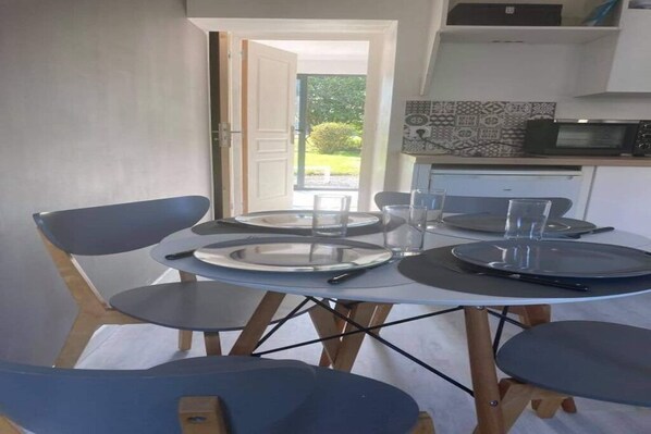 Un comedor con una mesa redonda, cuatro sillas y una cocina al fondo.