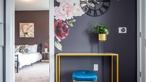 Une chambre à coucher comprenant un lit, une table de chevet, une horloge murale et une plante fixée au mur.