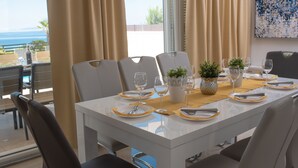 A dining table set for six with a view of the ocean.