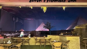 A restaurant with a view of pyramids, outdoor seating, and a bar area.