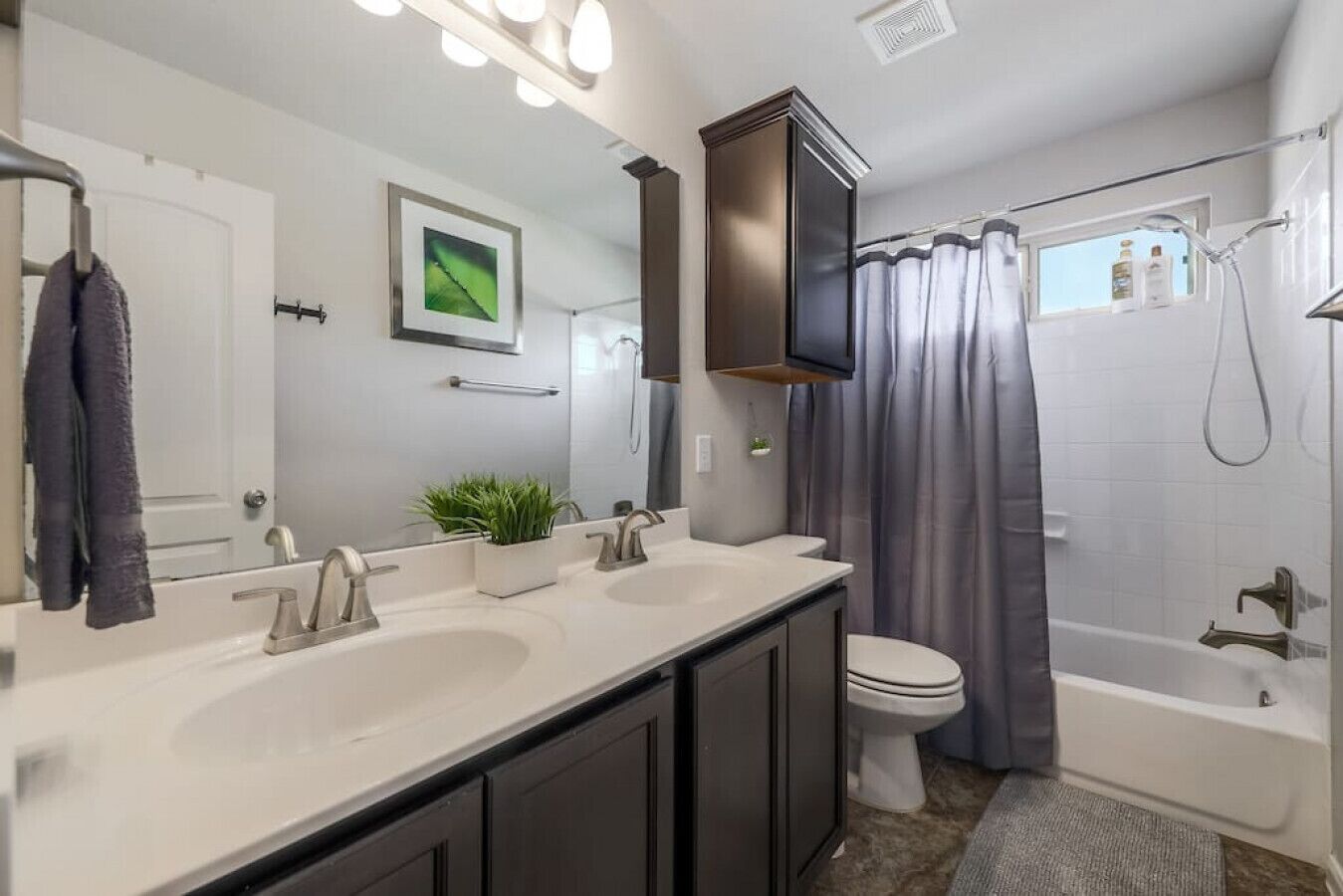 Une salle de bain moderne avec un meuble-lavabo à deux vasques, des toilettes, une douche avec rideau et un grand miroir.