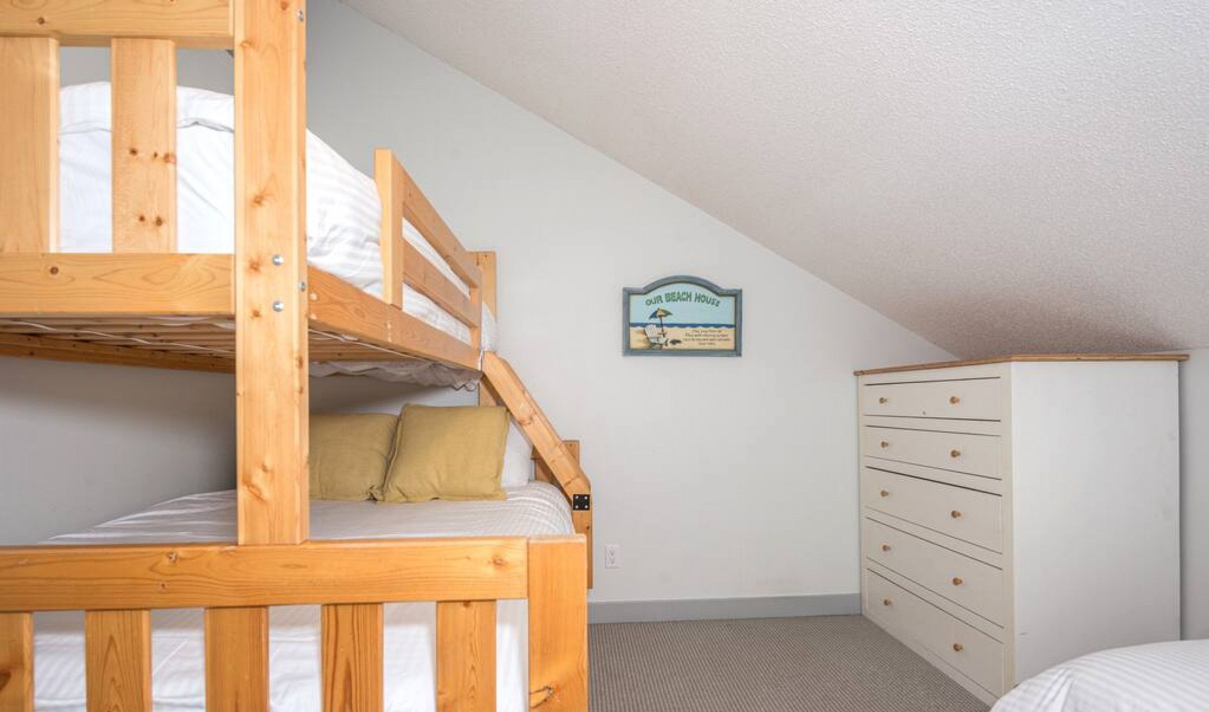 A dormitory room with bunk beds, a dresser, and a sign on the wall.