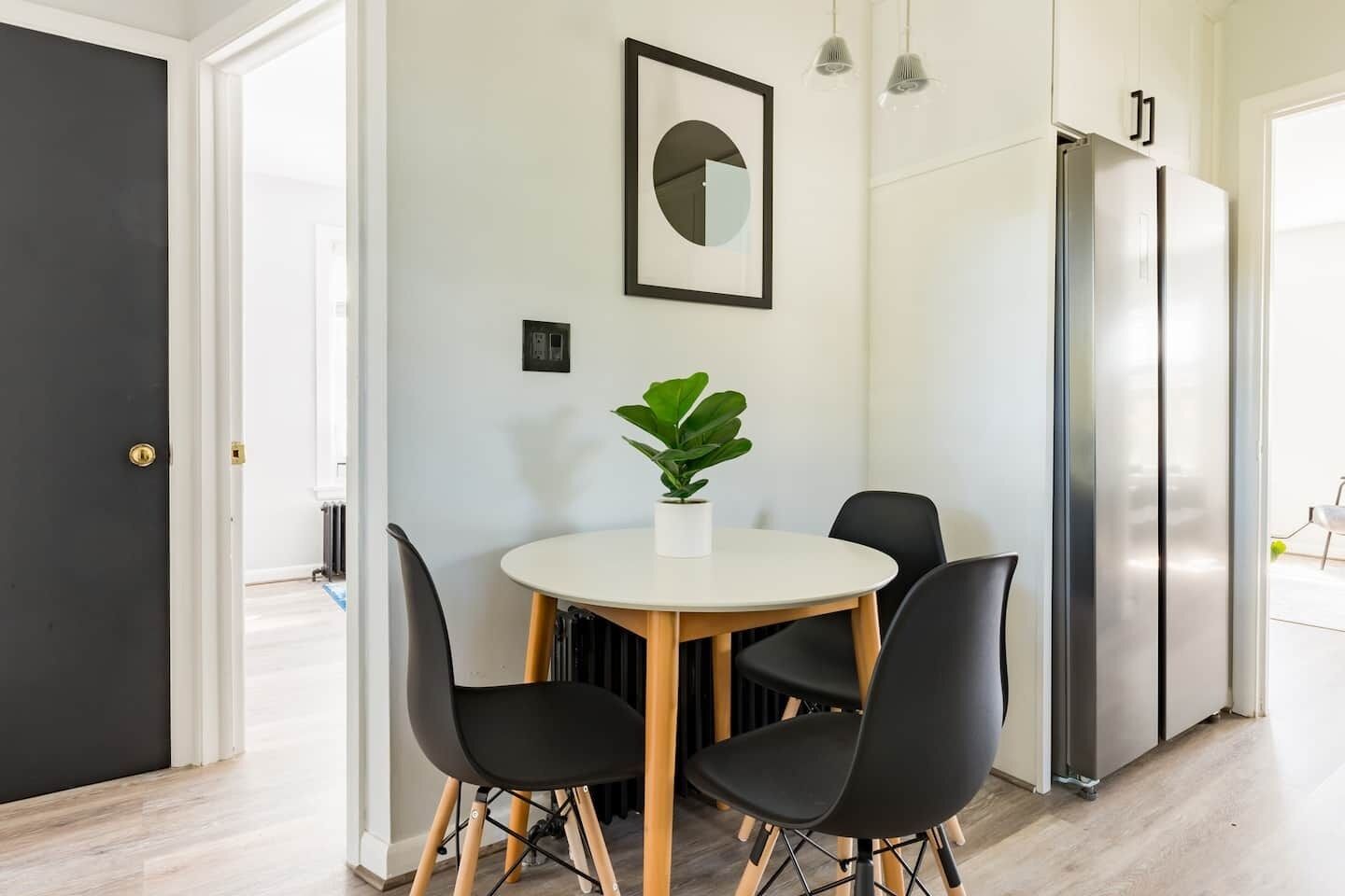 Une cuisine moderne avec une table à manger, des chaises, une plante en pot et un réfrigérateur.