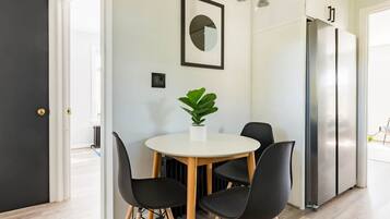 Une cuisine moderne avec une table à manger, des chaises, une plante en pot et un réfrigérateur.