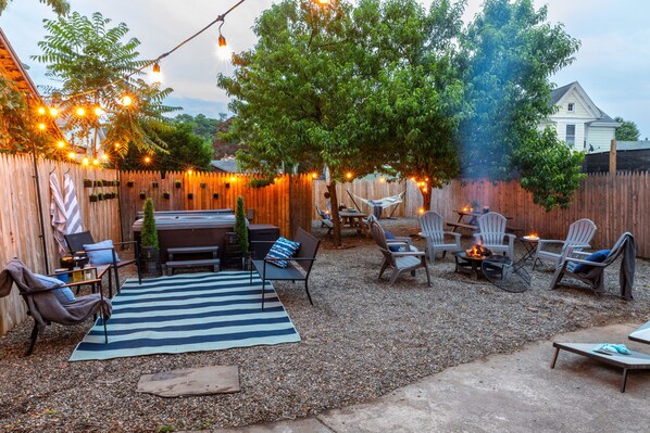 Un jardin avec un espace barbecue, des sièges et des guirlandes lumineuses.