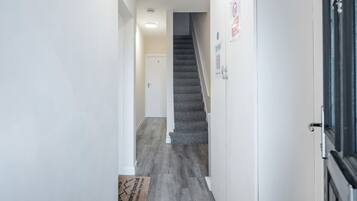 A hallway with a carpeted staircase, white walls, and a door at the end.