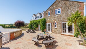 A stone building with a patio area featuring picnic tables and a barbecue grill. - Rookley Farm Lodge (Rookley)