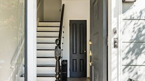 A modern house entrance with a dark door, a staircase, and a light fixture above. - Dog-Friendly Hudson Valley Escape with Hot Tub & Jacuzzi (Kingston)
