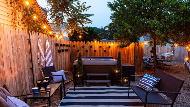 An outdoor patio with a striped rug, seating, a fire pit, and string lights. - Dog-Friendly Hudson Valley Escape with Hot Tub & Jacuzzi (Kingston)