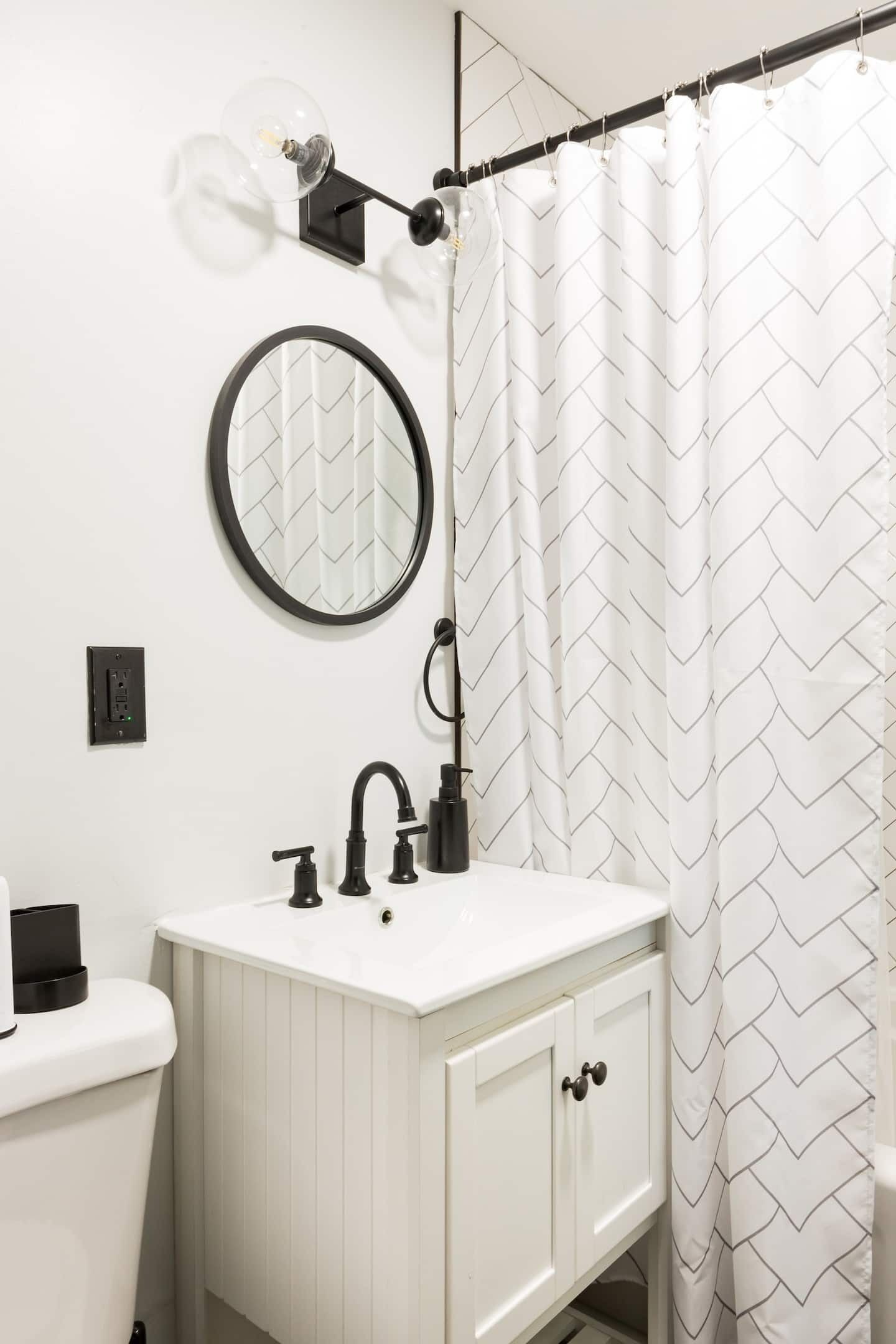 A bathroom with a white sink, black faucet, and a mirror above it.