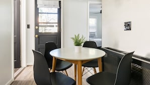 A dining area with a round table, black chairs, and a potted plant. - Dog-Friendly Hudson Valley Escape with Hot Tub & Jacuzzi (Kingston)