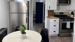 A modern kitchen with stainless steel appliances, a white dining table with a potted plant, and a welcome sign. - Dog-Friendly Hudson Valley Escape with Hot Tub & Jacuzzi (Kingston)