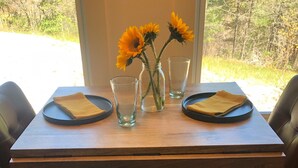 A wooden dining table with two chairs, a vase with sunflowers, and two glasses. -   Come enjoy this mountain retreat this Fall! (Saluda)