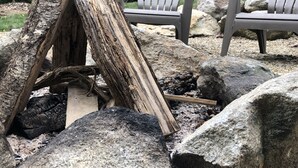 A rustic outdoor seating area with Adirondack chairs, a fire pit, and large rocks. -   Come enjoy this mountain retreat this Fall! (Saluda)