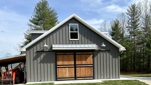 A single-story building with a large garage door, a small window, and a sloped roof. -   Come enjoy this mountain retreat this Fall! (Saluda)
