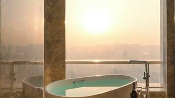 Un baño moderno con una bañera independiente, una ducha con mampara de vidrio y vistas a la ciudad.