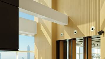A spacious lobby with high ceilings, wooden paneling, and large windows offering a city view.