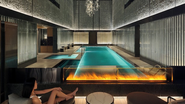 Un spa moderno con piscina central, zonas de estar y un elemento decorativo de fuego.