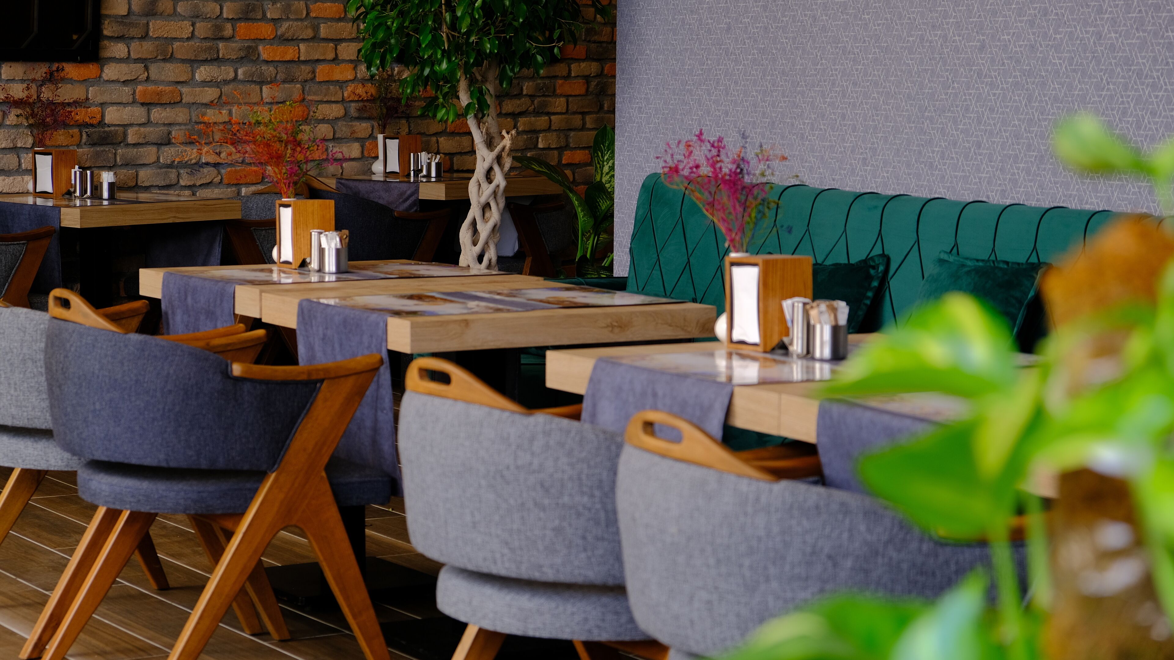Un ristorante con tavoli in legno e sedie grigie rivestite.