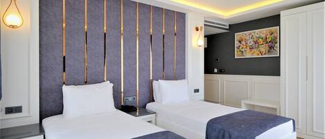 Une chambre d’hôtel moderne avec deux lits, un mur d’accent de couleur grise, un tableau et un luminaire au plafond.