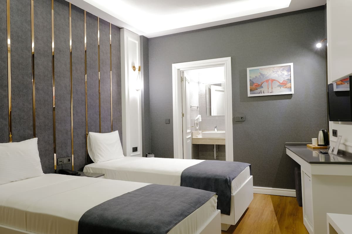 A hotel room with two beds, a desk, a mirror, and a TV.