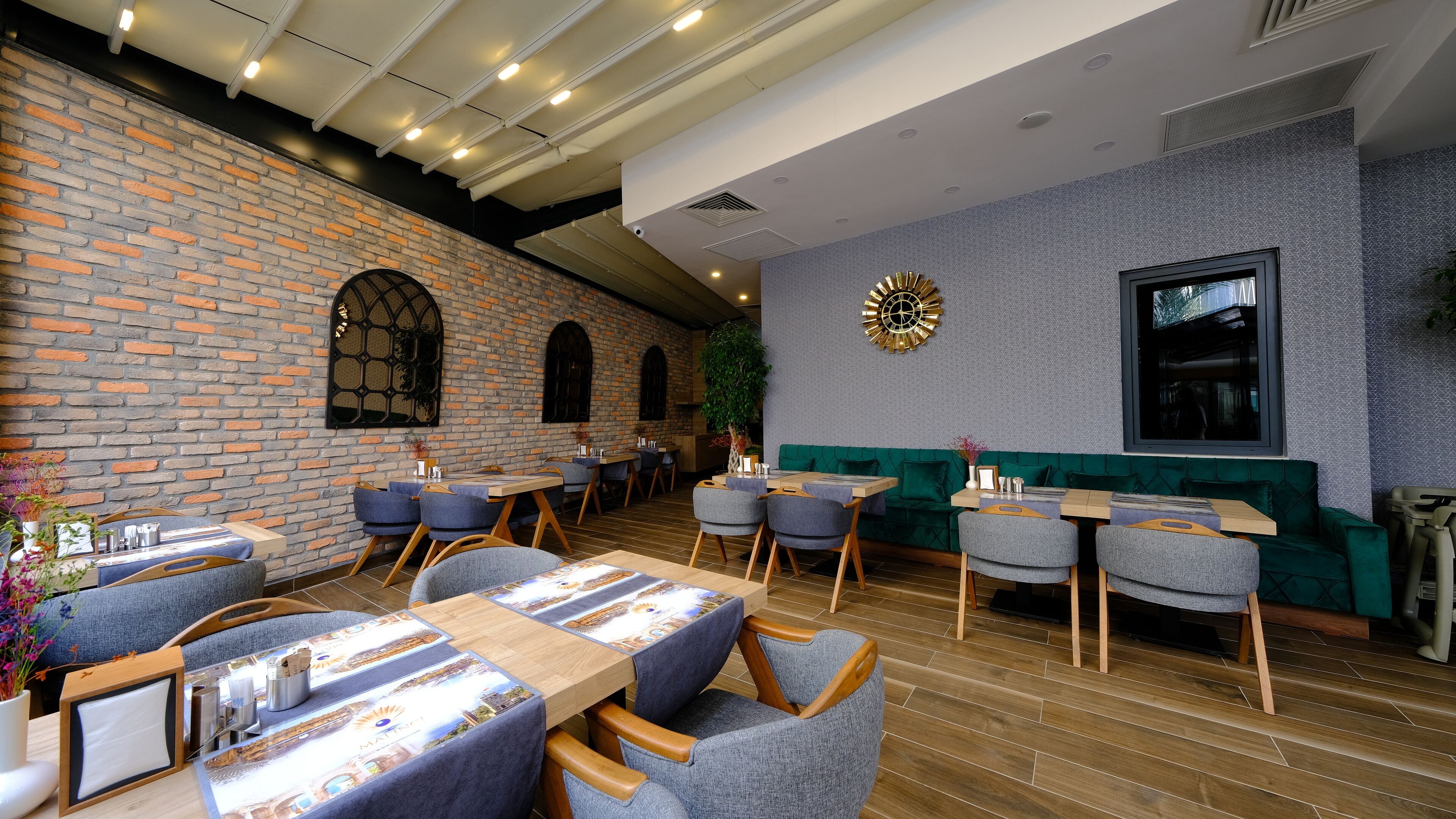 A restaurant with brick walls, wooden tables, and blue chairs.