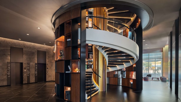 Un interior moderno con una escalera espiral central, estanterías empotradas y una amplia zona de recepción.